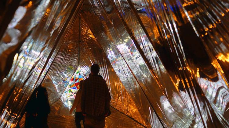 People walking through a reflective tunnel illuminated by colorful lights during the CityUps event at FESTA.
