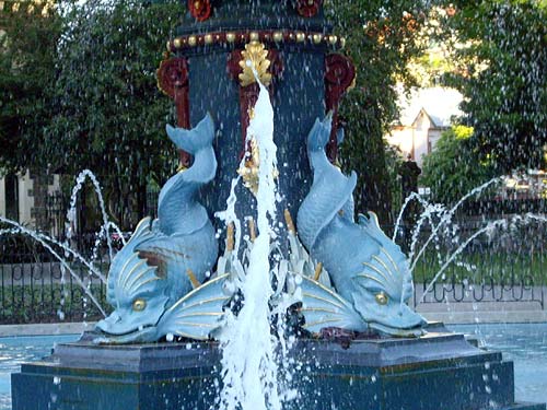 Close-up of the Peacock Fountain in the Christchurch Botanic Gardens featuring two artistic dolphin sculptures with water spraying from the central feature.