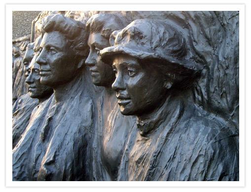 A close-up of a bronze monument featuring life-size figures of leading suffragettes, including Kate Sheppard, representing the New Zealand suffrage movement.