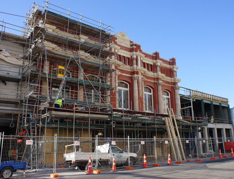 The Isaac Theatre Royal building undergoing restoration with scaffolding removed, showcasing its red brick facade and new construction elements on Gloucester Street.