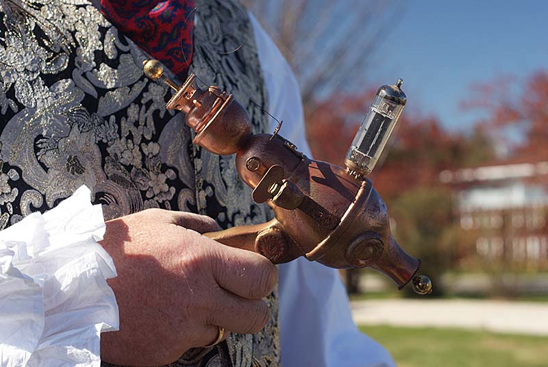 A close-up of a person's hand holding a vintage-style steampunk gadget with brass and glass components.
